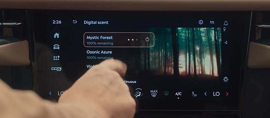 Car dashboard screen showing digital scent options, including "Mystic Forest" with a hand selecting it.
