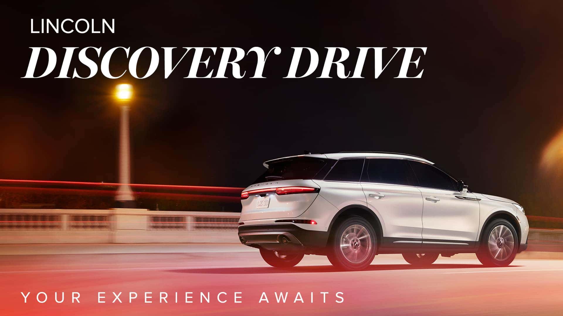 White Lincoln SUV on a lit road at night with "Lincoln Discovery Drive" and "Your Experience Awaits" text.