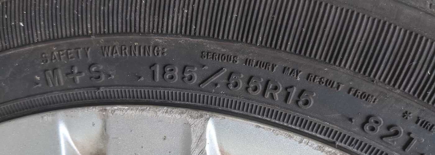 Close-up of tire size details (185/55R15) and safety warning on a vehicle tire sidewall.